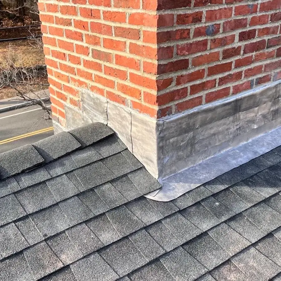 Metal flashing where a brick chimney meets an asphalt shingle roof