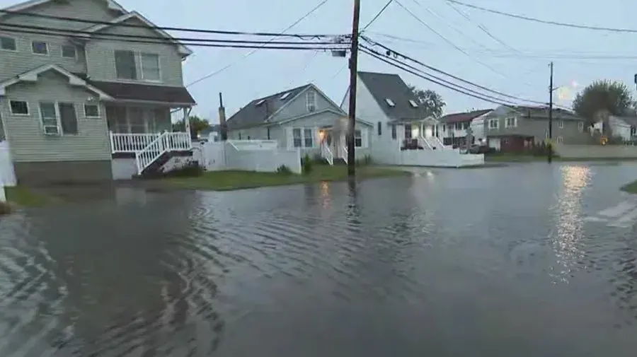 Floodwater covering a residential street in front of shore houses after a coastal storm